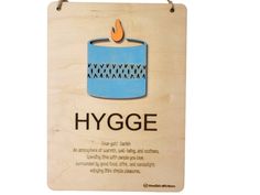 a wooden sign that says hygge with a lit candle in the middle