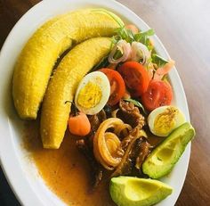 a white plate topped with sliced up bananas and veggies next to an egg