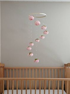 a baby crib with pink flowers hanging from the ceiling