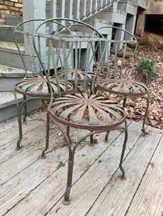 three metal chairs sitting on top of a wooden deck