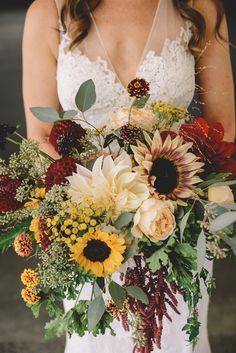 a woman holding a bouquet of flowers in her hands and wearing a wedding dress with lace