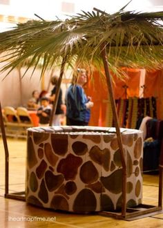 a giraffe print planter in the middle of a room with people standing around