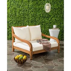 a couch sitting on top of a stone floor next to a wall covered in green plants