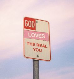 a red and white street sign that says god loves the real you with pink lettering on it