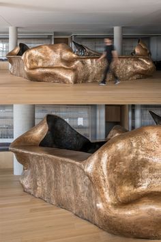 two images of a person walking past a sculpture in the middle of a room with wooden floors