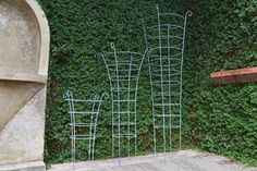 three metal planters sitting in front of a green wall