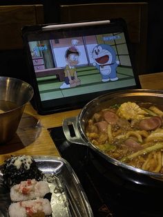 a cartoon character is on the computer screen in front of some food and sushi