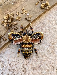 a bee brooch sitting on top of a floor next to some flowers and leaves