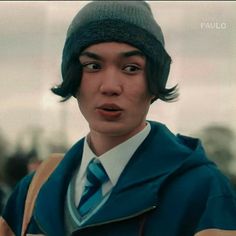 a young man wearing a blue tie and a green hat with his eyes wide open