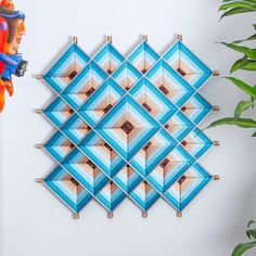 a blue and white wall hanging next to a potted plant