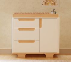 a white cabinet with drawers and a mirror on the wall above it in a room