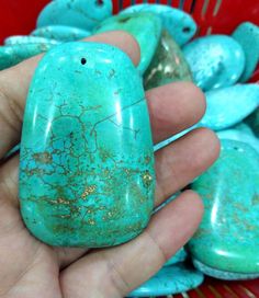 a person holding a turquoise colored stone in their hand