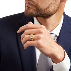 a man in a suit and tie wearing a gold ring