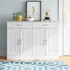 a white cabinet sitting on top of a wooden floor next to a blue and white rug