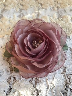 a pink flower sitting on top of a lace doily