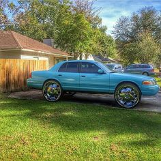 a blue car parked in front of a house on the side of a road next to a fence