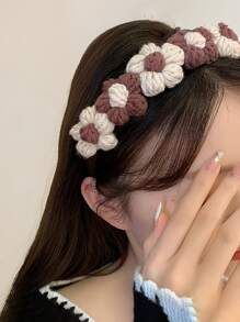 a woman covers her face with her hands while wearing a crocheted headband