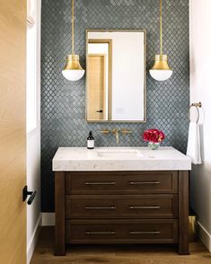 a bathroom with a sink, mirror and two lights on the wall above it's counter