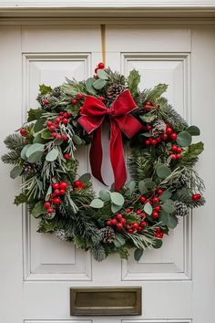 a christmas wreath on the front door of a house with holly, mist and berries