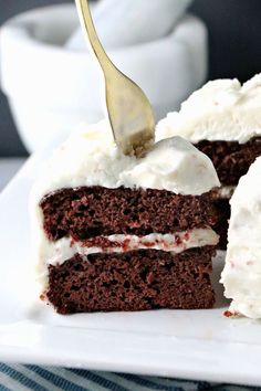 a piece of chocolate cake with white frosting and a fork sticking out of it