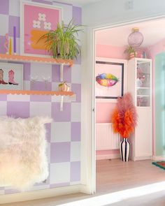 a pink and purple room with shelving, bookshelves and plants