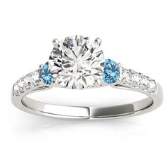 a diamond and blue topaz engagement ring with diamonds on the sides, set in 18k white gold