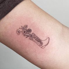 a small tattoo on the arm of a woman with flowers and a vase in it