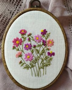 a close up of a embroidery on a piece of cloth with pink and yellow flowers