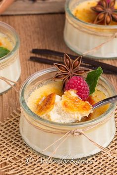 three desserts in small glass dishes with berries and cinnamon on the side, sitting on a woven place mat