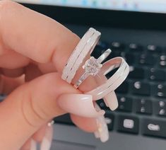 a person holding two rings in front of a laptop