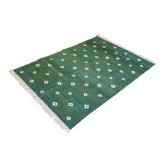 a green rug with white squares and diamonds on the bottom, in front of a white background