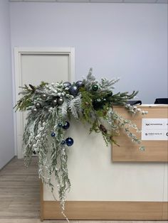 an office cubicle decorated for christmas with greenery and baubles hanging from the wall