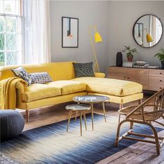 a living room filled with furniture and a large mirror on the wall above it's windows