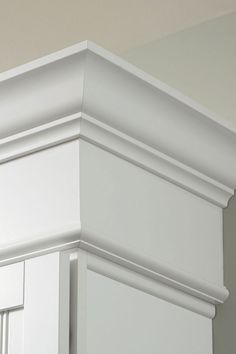 the corner of a kitchen cabinet with white paint and molding on it's sides