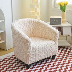 a white chair sitting on top of a red and white checkered floor next to a window