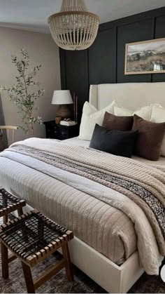 a bedroom with a bed, two chairs and a chandelier hanging from the ceiling