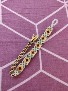 a white and yellow lanyard sitting on top of a purple tablecloth with geometric designs