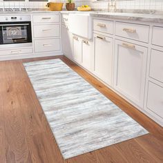 a kitchen with white cabinets and wood flooring on the wooden floor is an area rug that looks like it has been cleaned