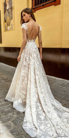 a woman in a white wedding dress standing on the side of a building with her back to the camera