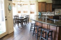 a kitchen with wooden floors and dark cabinets, counter tops, and bar stools