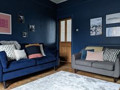 a living room with blue walls and couches, rugs and pictures on the wall