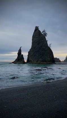 two large rock formations in the ocean on a cloudy day