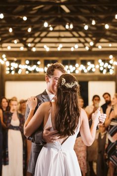 a bride and groom share their first dance at their wedding reception in front of an audience