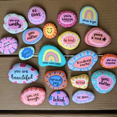 painted rocks that say you are brave and be kind to each other on a wooden surface