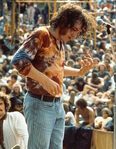 a man standing at a microphone in front of a large crowd with his hands out