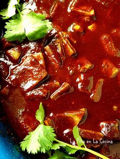 a blue plate topped with meat covered in sauce and garnished with cilantro