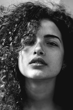 a black and white photo of a woman with curly hair looking off to the side