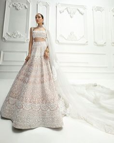 a woman in a wedding dress standing next to a white wall