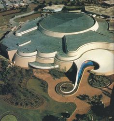 an aerial view of a large building in the middle of a city with lots of trees