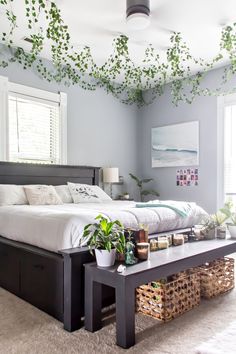 a bed sitting in a bedroom next to a table with plants on top of it